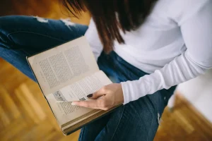 Pessoas lendo livro em ambiente interno, destacando a importância da leitura para desenvolvimento intelectual e lazer.