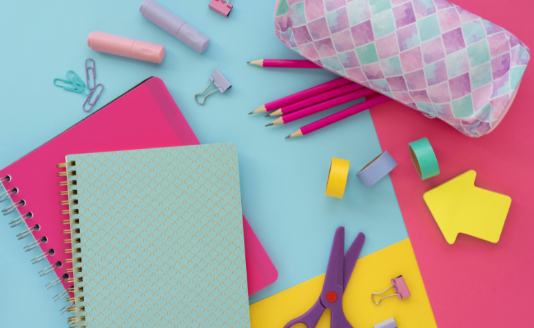 ferramentas-tecnologicas-para-sua-gestao-escolar Imagem de materiais escolares coloridos, incluindo cadernos, lápis, tesoura, fita adesiva, clipes, e uma bolsa de lápis, representando ferramentas tecnológicas para a gestão escolar.