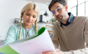 Professor ajudando estudante a se preparar para a redação do ENEM, ensinando técnicas de redação e leitura crítica para melhorar o desempenho na prova.