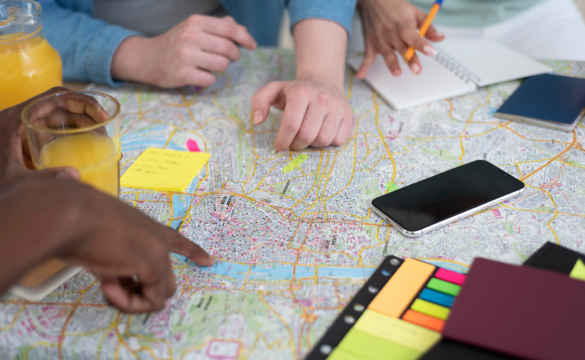 Estudantes discutindo estratégias para usar o Estatuto das Cidades na redação do Enem durante uma reunião com mapa, blocos de notas e celulares.