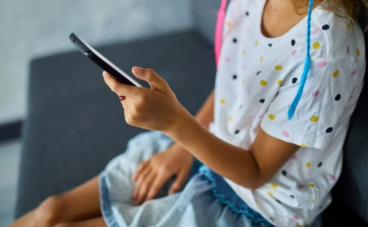 Criança usando um celular, refletindo o tema do repertório sociocultural sobre adultização e suas influências na infância.