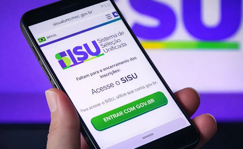 Uma mão segura um smartphone na posição vertical, exibindo a página oficial do SISU (Sistema de Seleção Unificada)